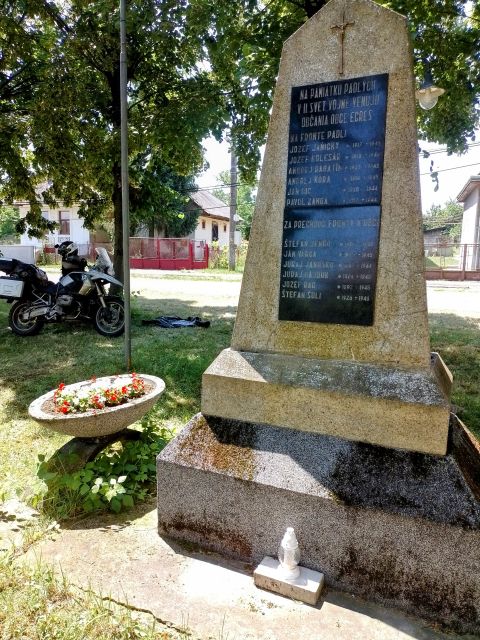 Ich mache eine Pause unter schattigen Bäumen, neben einem Denkmal für die Gefallenen des Zweiten Weltkriegs.