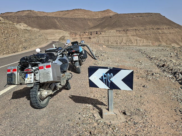 Rund um Mhamid erhebt sich eine karge, fast schon dramatische Landschaft. Flache Ebenen gehen über in schroffe, dunkle Gebirgszüge, die wie eine natürliche Barriere wirken. 