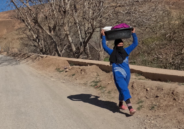 Frau auf dem Weg mit ihrer Wäsche zum Fluss